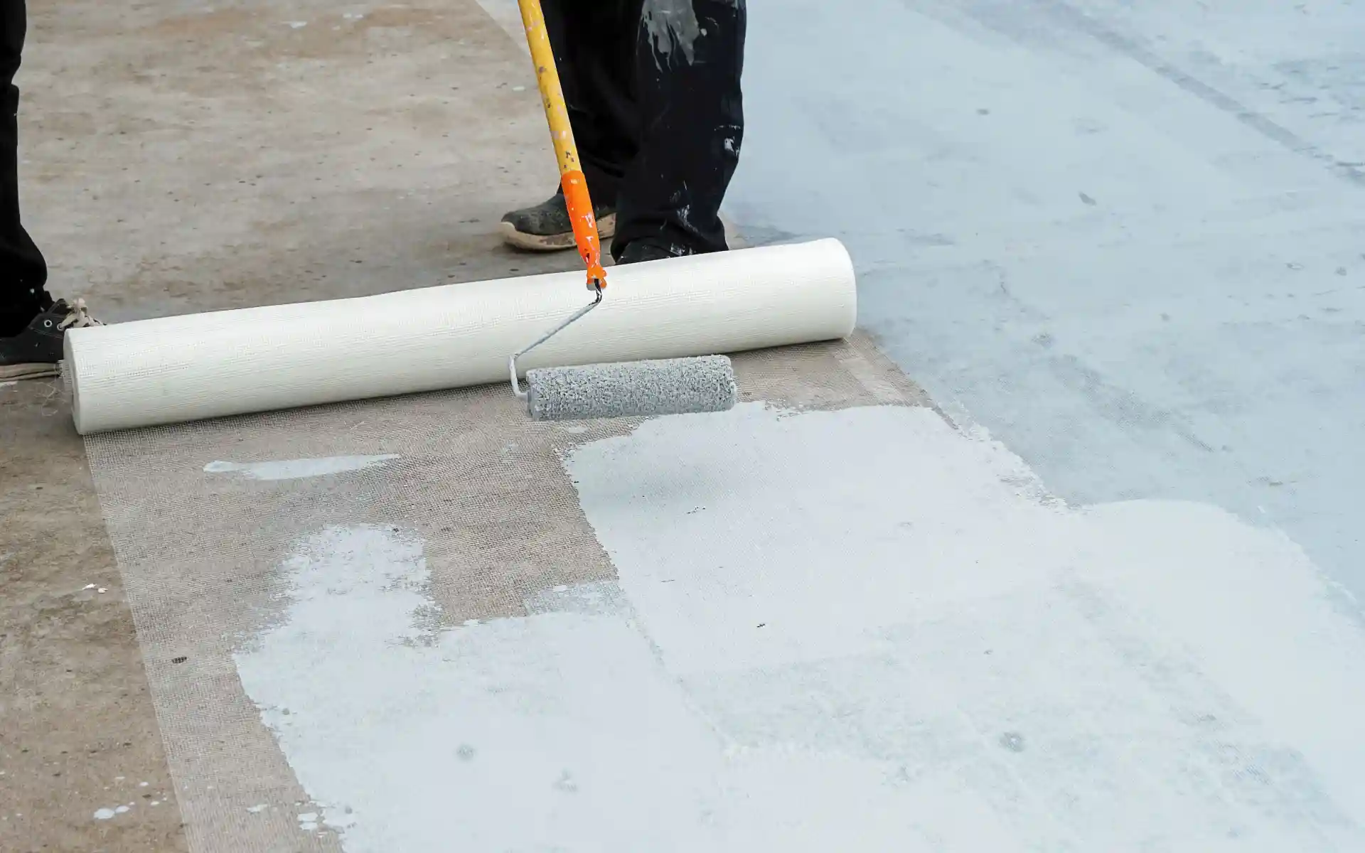 A man was using a roller to paint a floor, focusing on achieving an even coat of paint.